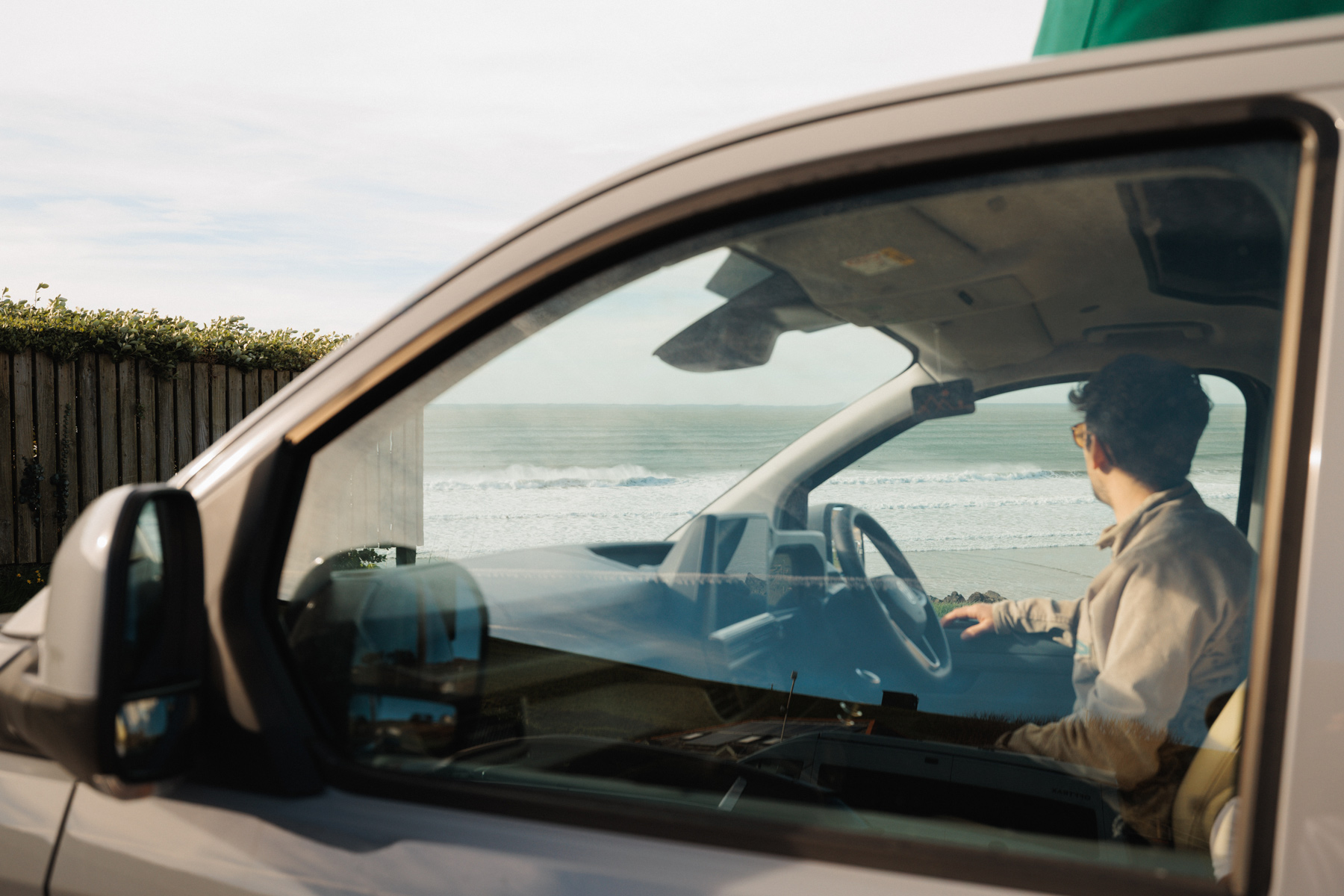 Campervan owner looking out at the sea from the driver's seat